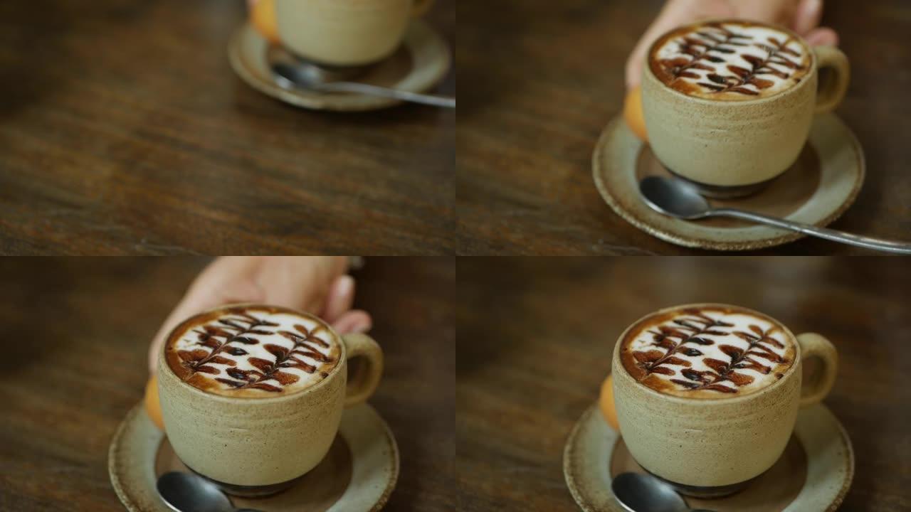 咖啡师在桌子上放了一杯拿铁咖啡。手把一杯咖啡和牛奶放在咖啡馆里。咖啡休息。特写