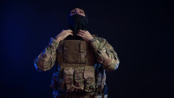 一名身穿军装的男子戴着头盔，背景是黑色