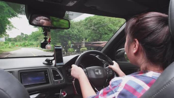 后视图亚洲妇女开车沿着森林小径行驶。日光驾驶