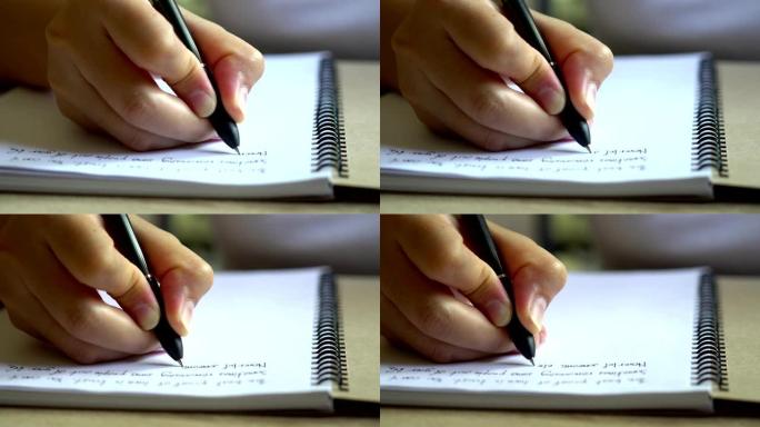 一个女人的手在桌子上写空白笔记本