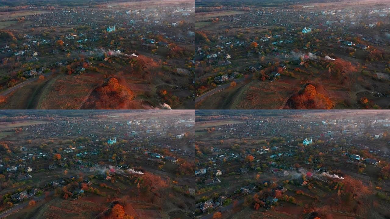 乌烟瘴气的乌克兰村庄鸟瞰图中的秋天日落。使用无人机进行空中录像。秋季景观: 乌克兰村庄，设有教堂和一