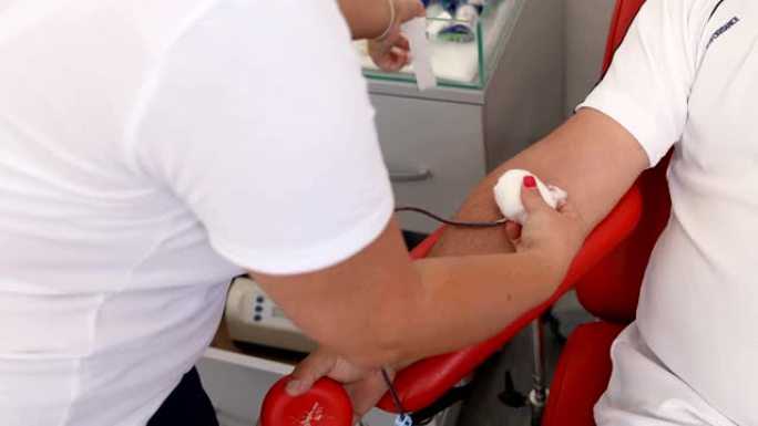 护士从捐献者手中取出医用针头。善行。为身体献血的好处。接受输血的接受者的手。在医疗诊所献血的特写