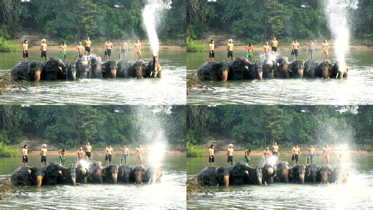 慢动作拍摄的年轻人穿着传统的泰国服装骑在河里美丽的大象上。大象从它的树干里吹水。