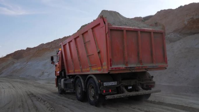 在尘土飞扬的土路上运送沙子的重型卡车