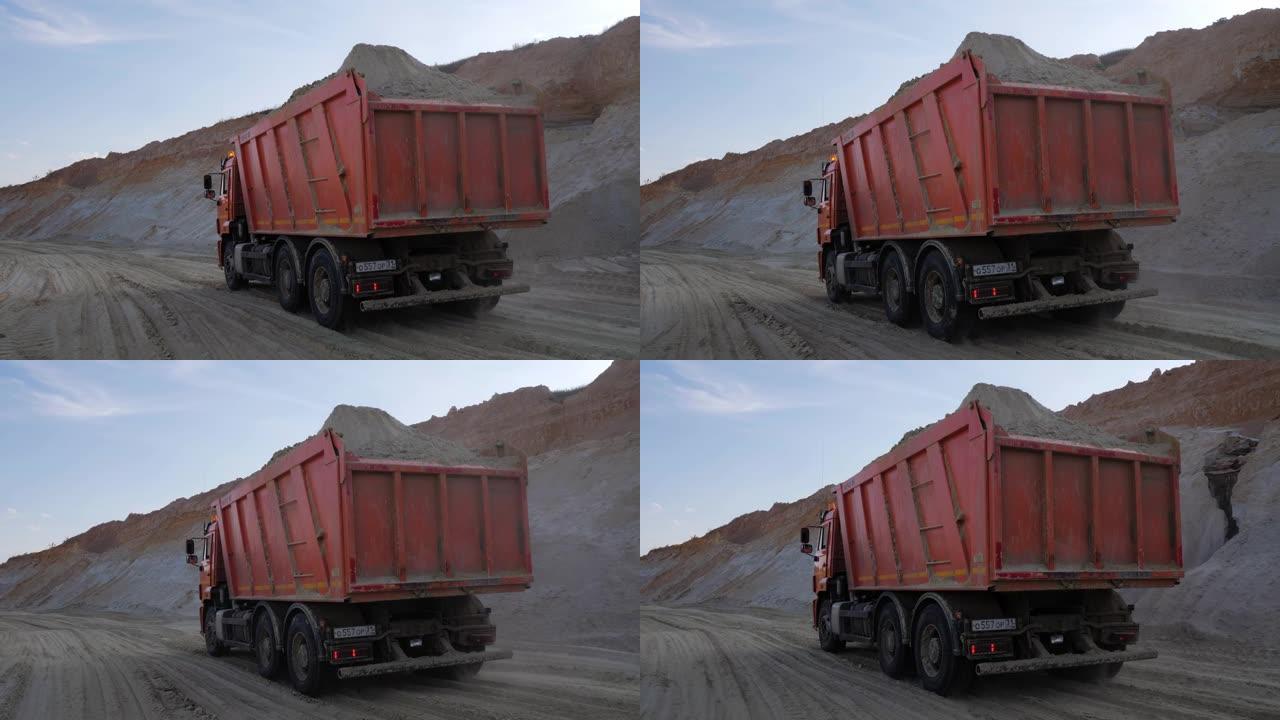在尘土飞扬的土路上运送沙子的重型卡车