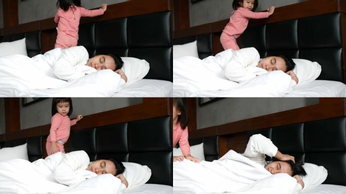 可爱的亚洲小女孩早上躺在家里的床上叫醒妈妈。