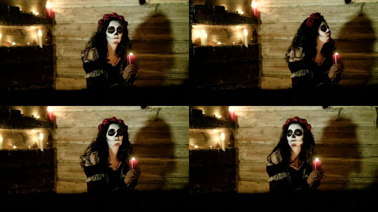 带着可怕的骷髅万圣节化妆的年轻女子手持点燃的蜡烛。高清