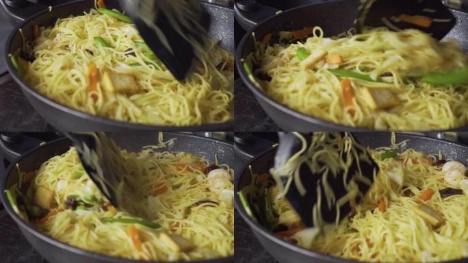 女士在平底锅上炒清炒蔬菜和米粉。中国菜。