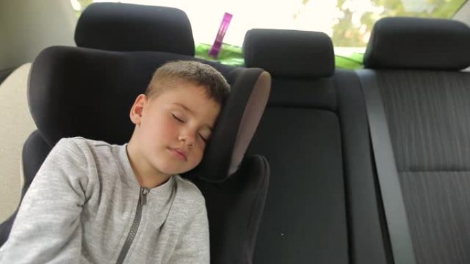 度假期间公路旅行时睡在汽车安全座椅上的疲惫小孩