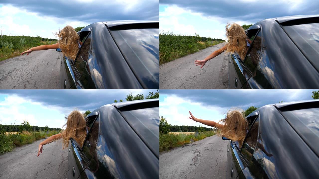 无忧无虑的小女孩在穿越乡间小路时，从车窗外倾斜，在风中挥舞着手。小孩将手臂伸出敞开的窗户，自动移动以