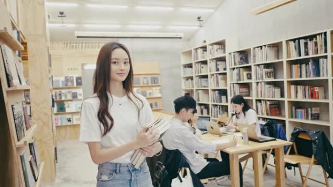 一名年轻的亚洲女学生站在图书馆的肖像