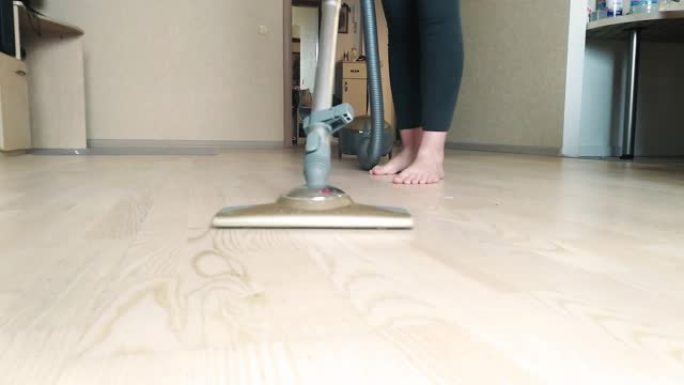 一个有吸尘器的女人在家打扫地板。