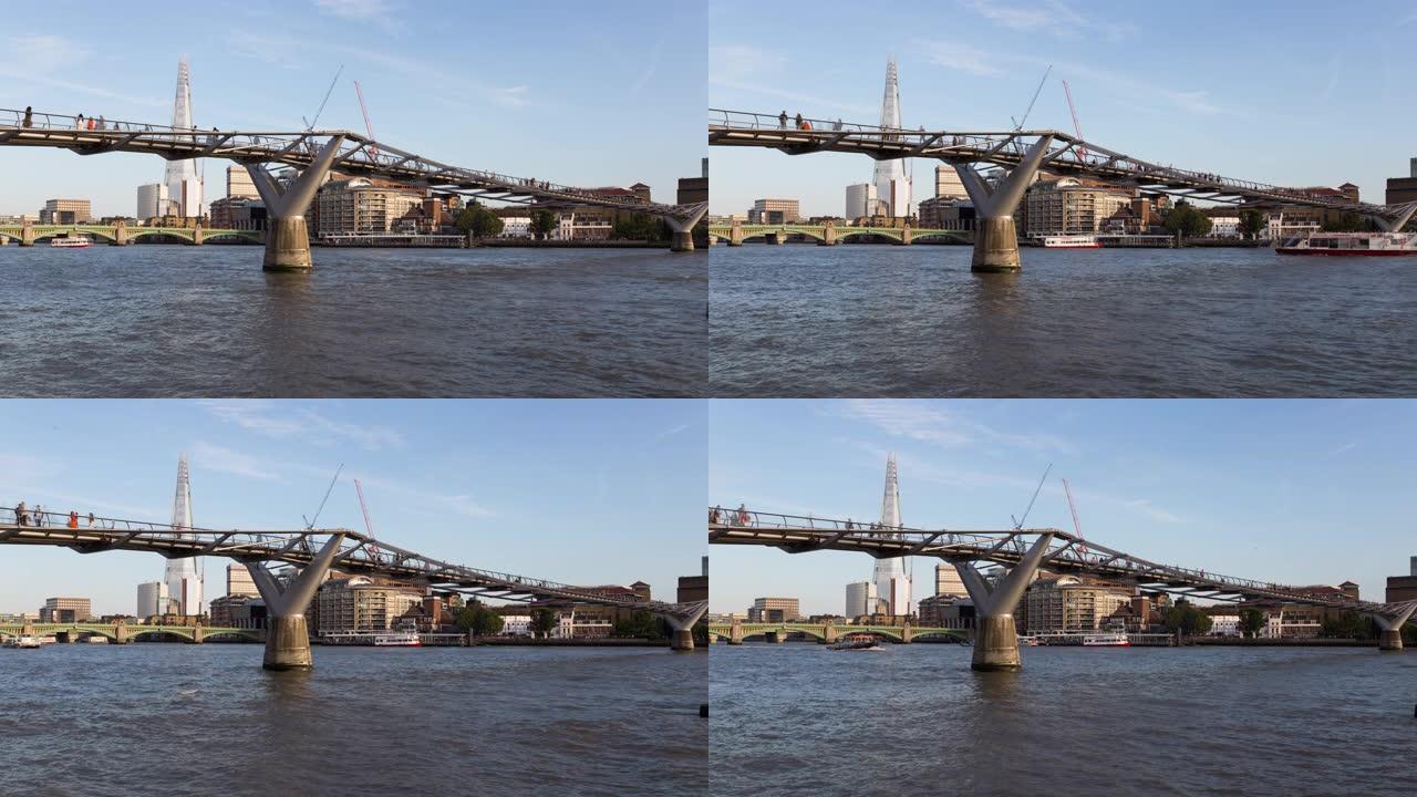 在千禧桥上行走的人们和泰晤士河上的渡轮