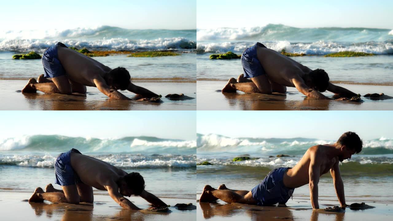 穿着蓝色短裤的肌肉体操运动员在海滩上练习瑜伽