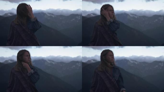 一个年轻浪漫女孩的肖像，背景是山。一个美丽的女孩看着夕阳，在雪山后面。悲伤或思考