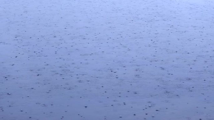 雨滴落在水面上。雷暴期间，大雨滴落入水坑。水滴。大雨落下背景