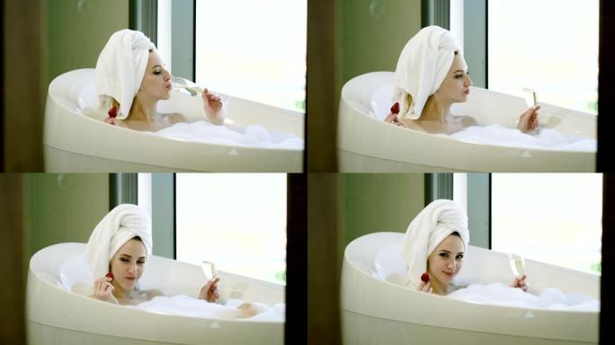 幸福的女人，头上戴着浴巾，在浴室里洗泡泡浴，吃草莓，喝香槟。4 k
