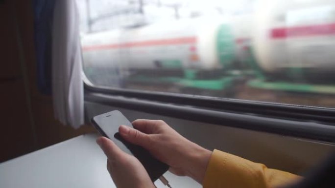 在步行火车的窗户背景上使用智能手机
