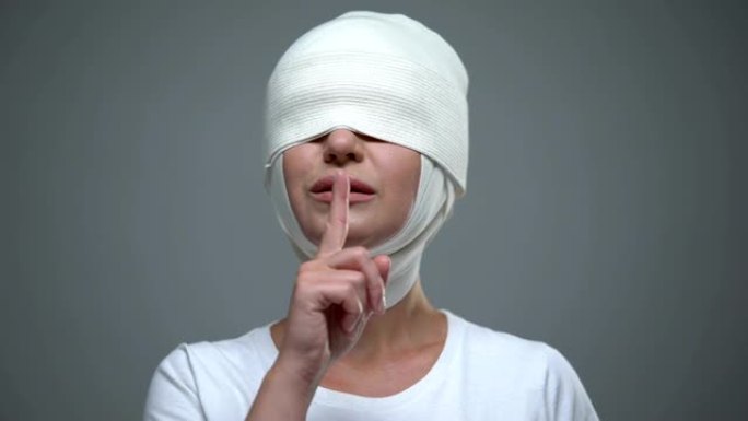 戴头巾的女人表现出沉默的手势，抬起脸和矫正视力