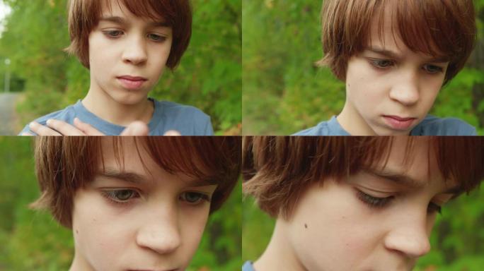 特写脸和眼睛少年男孩在绿色的夏日树木背景。肖像男孩少年在户外看东西。