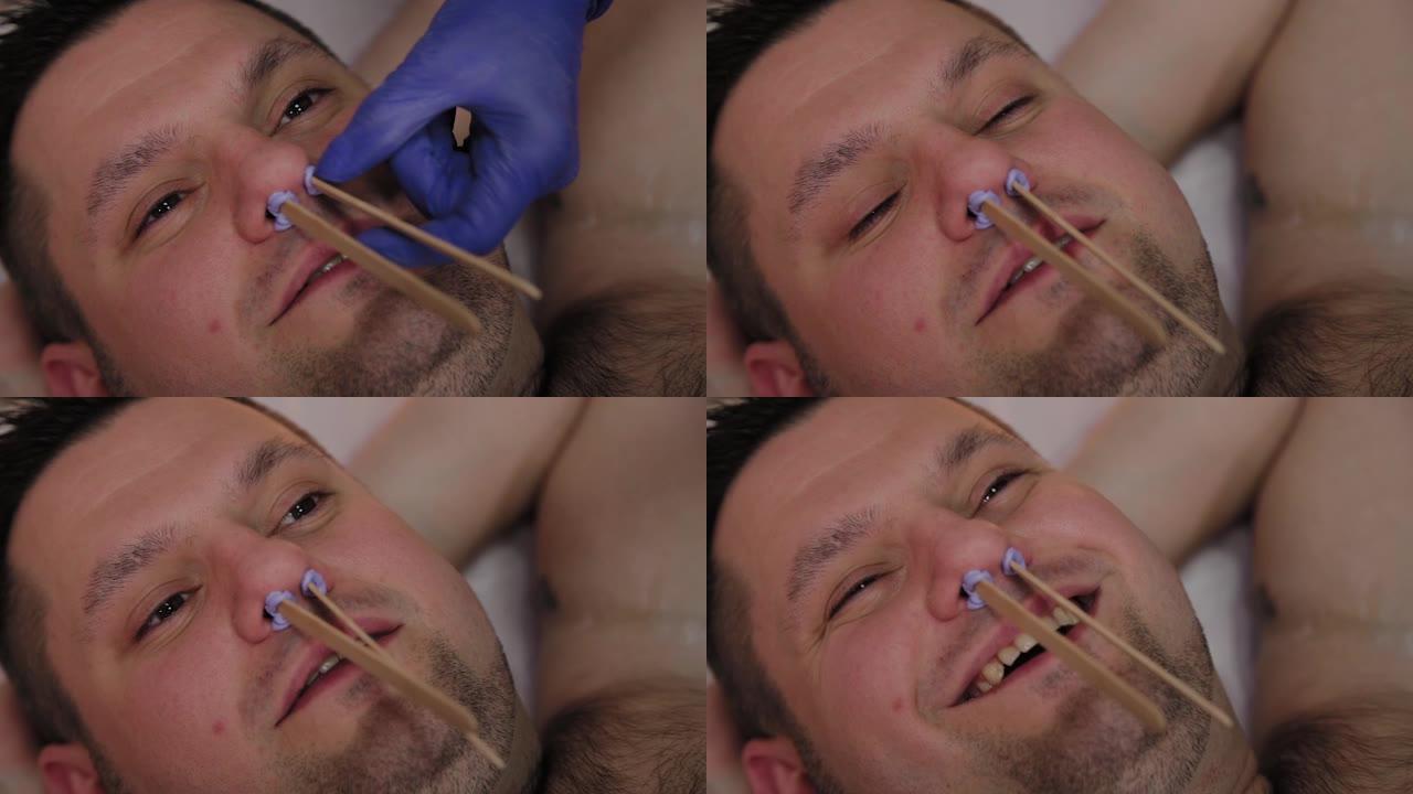 专业美容师在男人的鼻子上打蜡