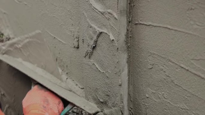 专业建筑工人在墙上抹灰水泥。慢动作