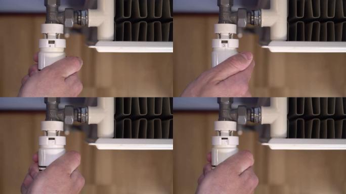 手转动白色供暖散热器的恒温器，以降低室内供暖温度