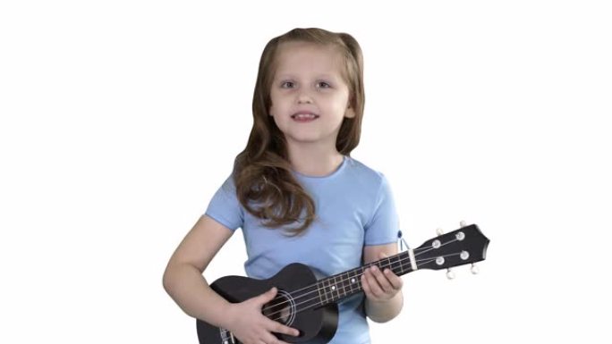 小女孩在白色背景上走向相机时唱歌和弹小吉他