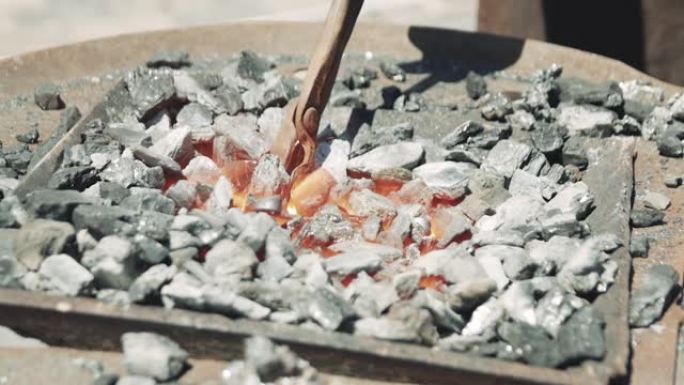 在铁匠铺的煤锻炉中，用火焰加热了热金属棒。金属零件正在炉中加热，并准备在铁匠车间锻造。