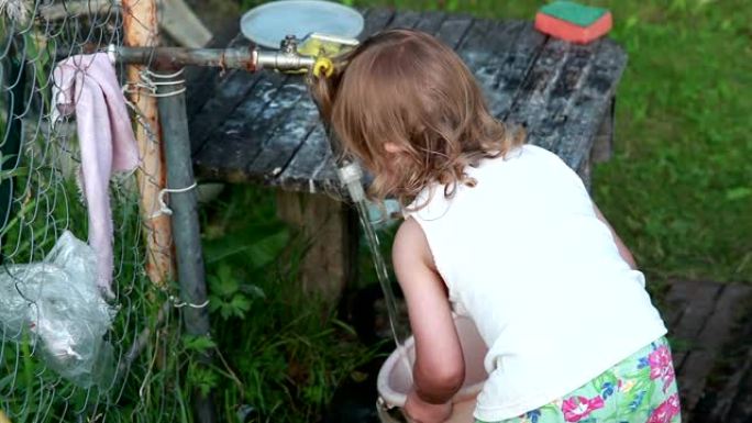 小女孩用花园水龙头的水装满水桶