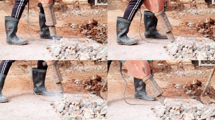 亚洲工人在使用电动手提钻打破混凝土地板时，土木建筑概念。