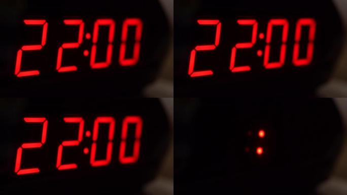 黑色数字时钟屏幕的特写显示22.00。黑色背景上闪烁的数字。现代定时器和红色霓虹灯、电气设备和现代技
