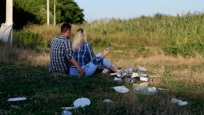 不负责任的青少年坐在公园里的草地上，周围是垃圾。
