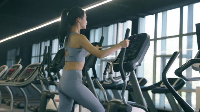 穿运动内衣的年轻女性在健身房使用跑步机