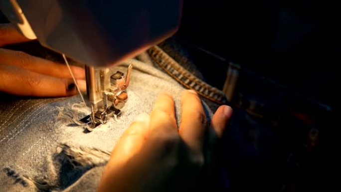 4k镜头。一个女人用缝纫机缝制蓝色牛仔牛仔裤的特写镜头