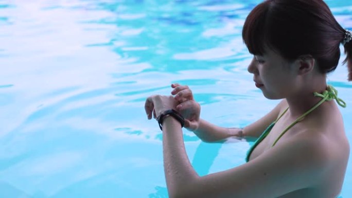 使用智能手表并在可穿戴技术设备的游泳池中检查的年轻亚洲女性