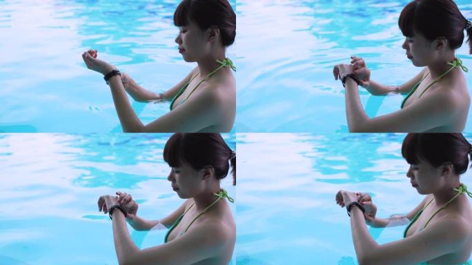 使用智能手表并在可穿戴技术设备的游泳池中检查的年轻亚洲女性