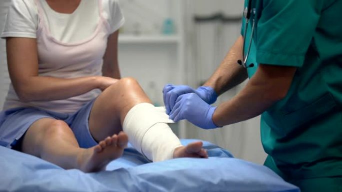 男性外科医生对女性患者的腿部进行弹性包裹，康复期