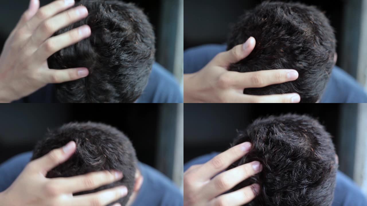两只手在一个孤立在黑色背景上的白人男性青少年的头上做头发按摩。