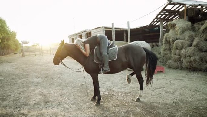漂亮的女骑士在乡村牧场拥抱和亲吻马。爱情、友谊、农场动物的概念。慢动作。
