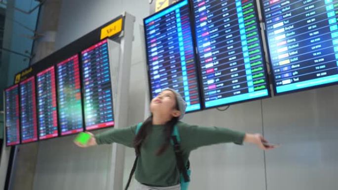 亚洲小女孩在机场的旅程，检查航班时刻表，伸出双臂