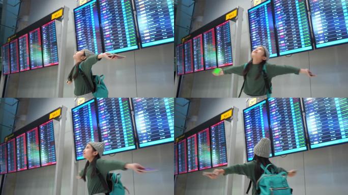 亚洲小女孩在机场的旅程，检查航班时刻表，伸出双臂