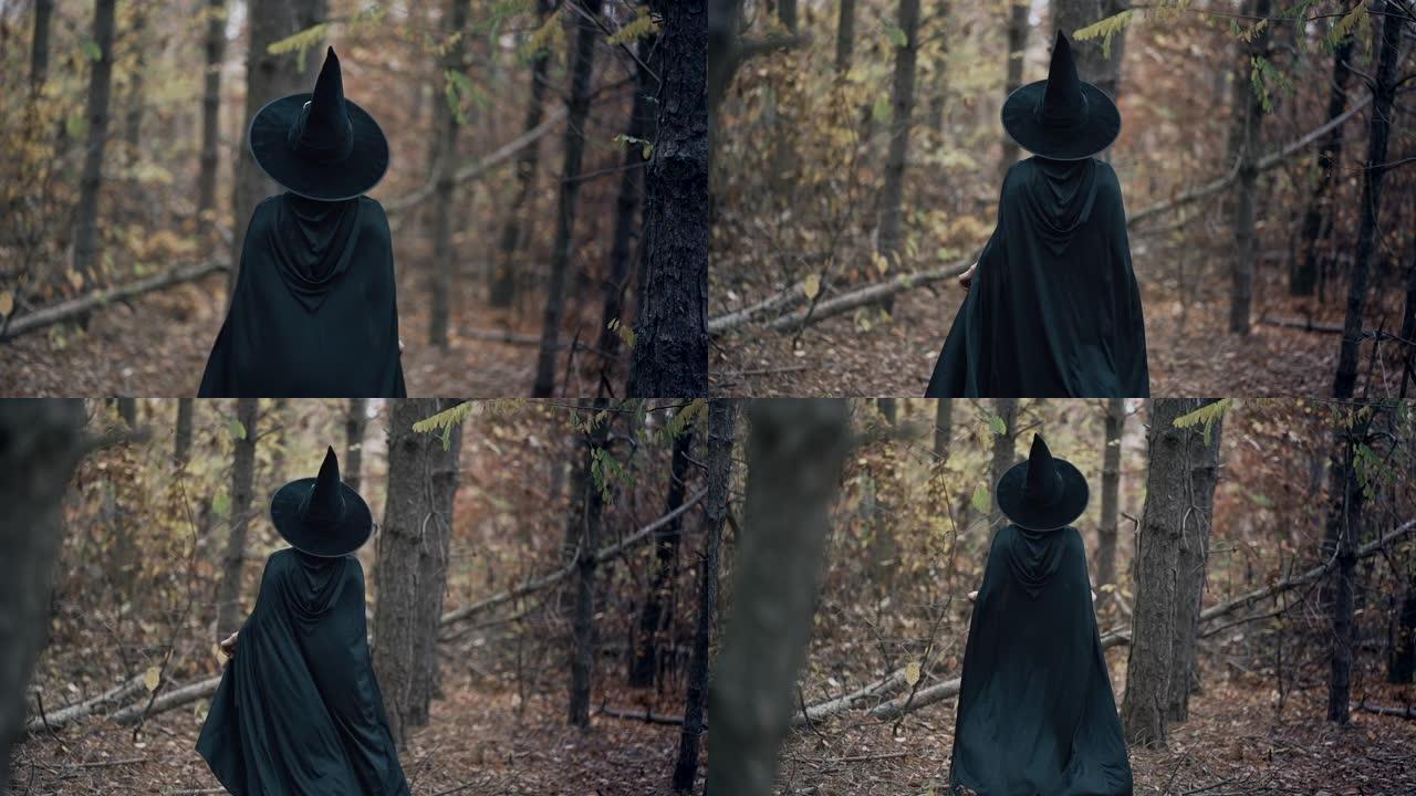黑色女巫在秋天的森林中漫步在树木之间，无法辨认的女人。穿着长裙，斗篷，仙女帽的女孩。万圣节概念，角色