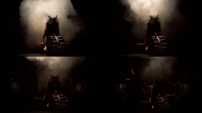 四位艺术家在舞台上戴着喇叭和化妆鼓的假发鼓鼓Taiko在黑暗的背景下冒烟。日本神话中的恶魔。没有声音