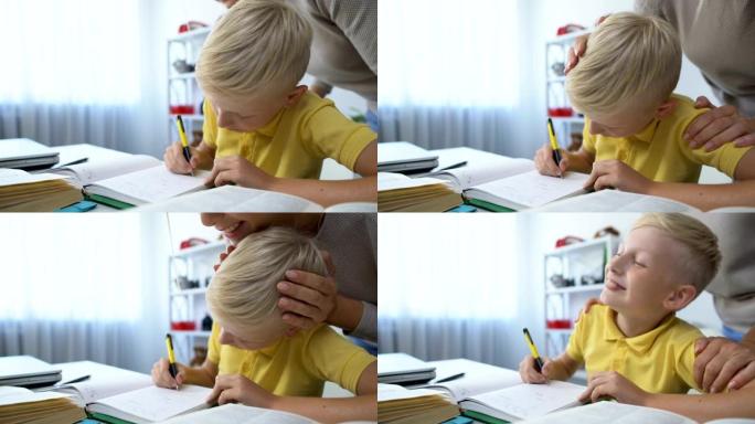 勤奋的男孩在桌前做作业，妈妈表扬儿子，摸着头