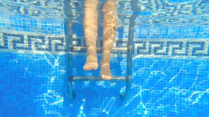在游泳池的金属楼梯上冷却的脚的淹没视图