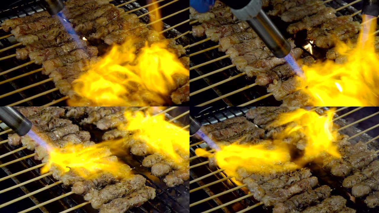 厨师烧烤牛肉或牛排，在泰国街头食品的烤架上插入烟雾和火焰。