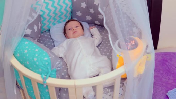漂亮宝贝躺在家里的摇篮里。新生婴儿躺在婴儿床里微笑。