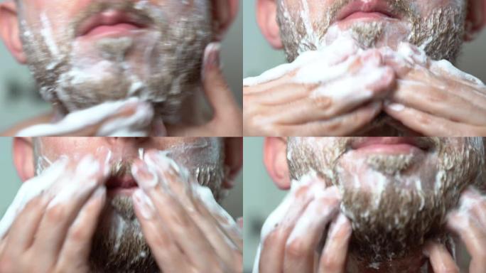 残忍的人呆在镜子前，用剃须放松的洗发水给他没刮胡子的胡子涂肥皂。用电动修剪器准备刮胡子的人。剃光理发