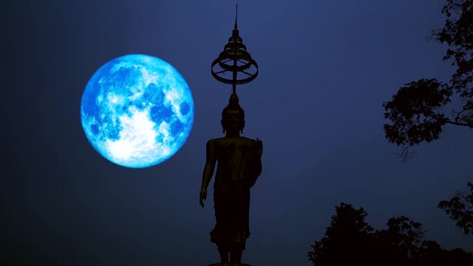 满蓝的收获月亮在夜空和剪影佛像上移动